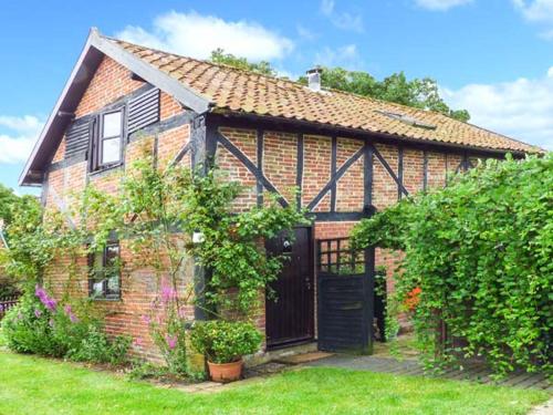 uma casa de tijolos com uma porta preta num quintal em The Granary em Norwich