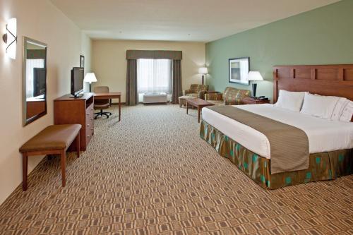 a hotel room with a large bed and a living room at Holiday Inn Express & Suites Ripley by IHG in Ripley