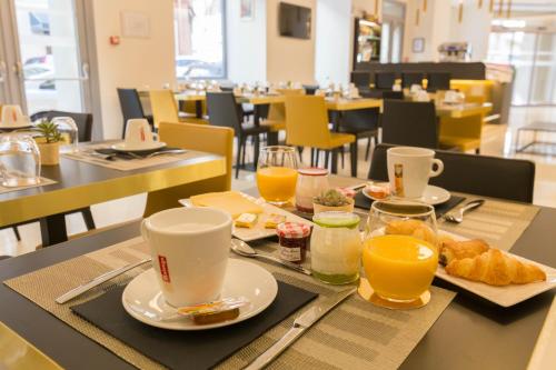 a table with a tray of breakfast foods and orange juice at Hôtel Nice Azur Riviera in Nice