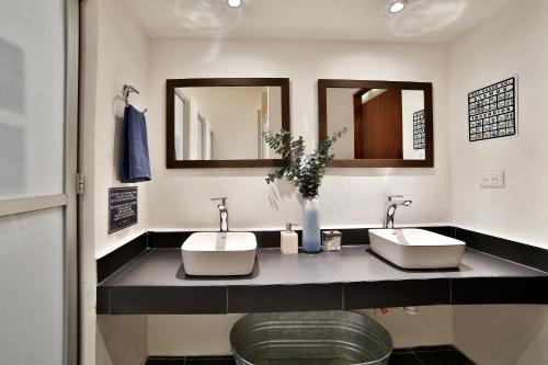 a bathroom with two sinks and two mirrors at Hostal Ten to Ten Puerto Vallarta in Puerto Vallarta