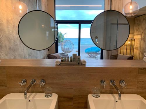 two sinks in a bathroom with two mirrors at Playa Grande by Tropical - Adults Only in Gavà
