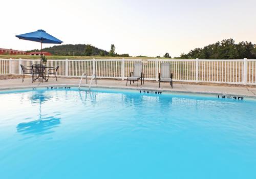 a swimming pool with two chairs and an umbrella at Holiday Inn Express Hotels & Suites Mountain Home, an IHG Hotel in Mountain Home