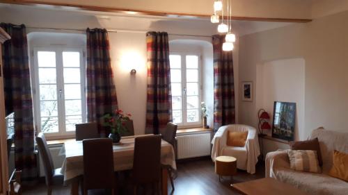 a living room with a couch and a table and two windows at L étoile du verger in Barcelonnette