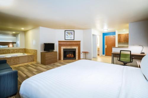 a hotel room with a bed and a fireplace at Holiday Inn Express & Suites Rocky Mount Smith Mountain Lake by IHG in Rocky Mount