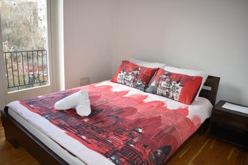 ein Bett mit einer roten Bettdecke und zwei weißen Handtüchern darauf in der Unterkunft Apartment Tino in Zagreb