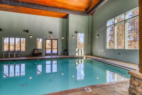 an indoor pool with blue water in a house with windows at Lift A4 Condo in Angel Fire