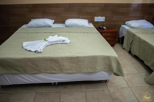 two beds in a room with a white robe on it at Bento palace hotel in Assis