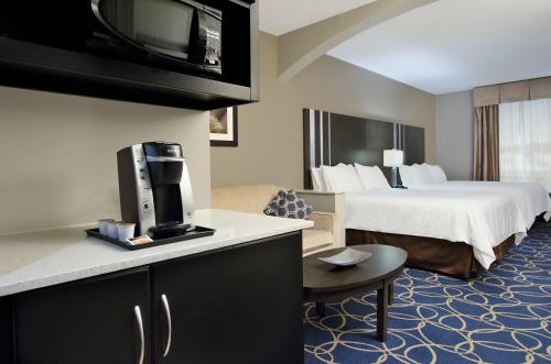 ein Hotelzimmer mit einem Bett und einem Fernseher in der Unterkunft Holiday Inn Express and Suites Houston North - IAH Area by IHG in Houston