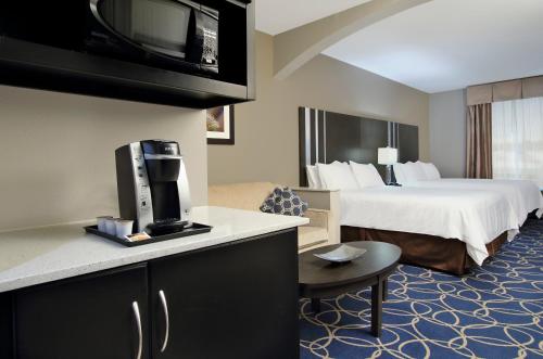 a hotel room with a bed and a tv at Holiday Inn Express and Suites Houston North - IAH Area, an IHG Hotel in Houston