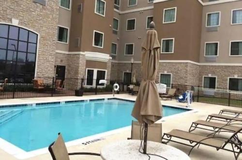 einem Pool mit einer Statue vor einem Gebäude in der Unterkunft Staybridge Suites - Denton, an IHG Hotel in Denton