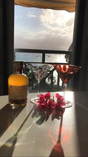 a bottle of wine and two glasses on a table with flowers at SUBLIME T 3 AU GOSIER 2 CHAMBRES VUE MER in Le Gosier