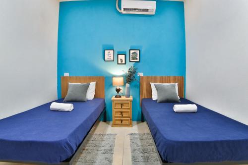 2 camas en una habitación con paredes azules en Hostal Ten to Ten Puerto Vallarta en Puerto Vallarta