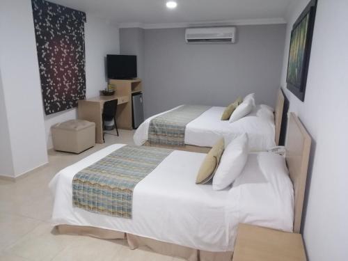 a hotel room with two beds and a desk at Hotel Buena Vista Express in Bucaramanga