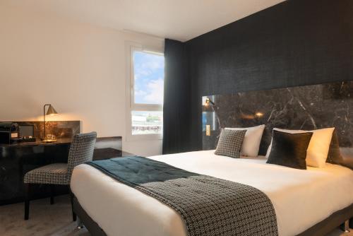 1 dormitorio con 1 cama grande y escritorio en The Originals City, Hôtel Orléans Nord (Inter-Hotel) en Saran