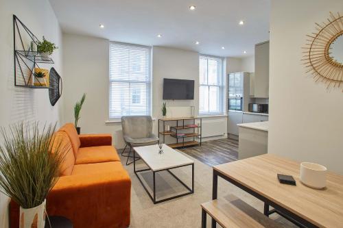a living room with an orange couch and a kitchen at Host & Stay - Apartment One, Hudsons Yard House in Whitby