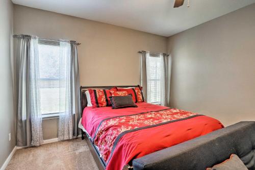 Schlafzimmer mit einem Bett mit roter Bettwäsche und Fenstern in der Unterkunft Pet-Friendly Family Home in Hutto with Private Yard! in Hutto