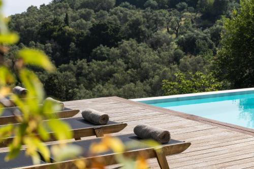 a wooden table next to a swimming pool with two tires at Villa Bella Vista Corfu in Kassiopi
