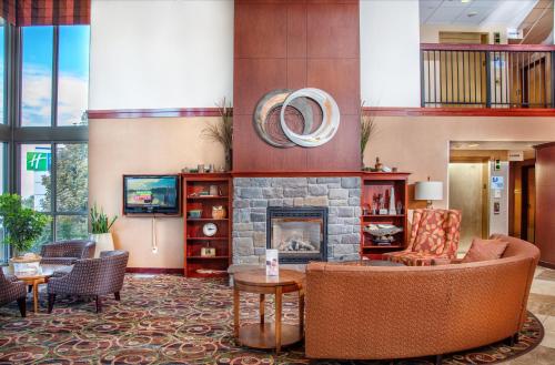 a lobby with a fireplace and a couch and chairs at Holiday Inn Express Hotel & Suites Richland in Richland