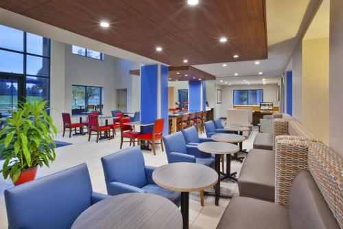 a restaurant with blue chairs and tables and chairs at Holiday Inn Express Rochester-Victor, an IHG Hotel in Victor