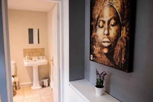 a bathroom with a painting of a woman on the wall at 4 Bedroom House- Close to City Centre- Ideal for Contractors- Free Parking- Sleeps 8 in Stoke on Trent