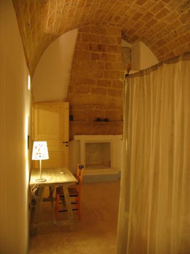 a room with a table with a lamp and a fireplace at Corte Dei Nonni in Presicce