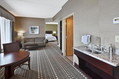 a hotel room with a sink and a bedroom at Holiday Inn Express & Suites Geneva Finger Lakes by IHG in Geneva