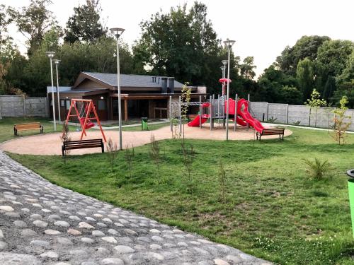 a park with a playground with two slides and benches at Villarrica Condominio Costanera Playa in Villarrica