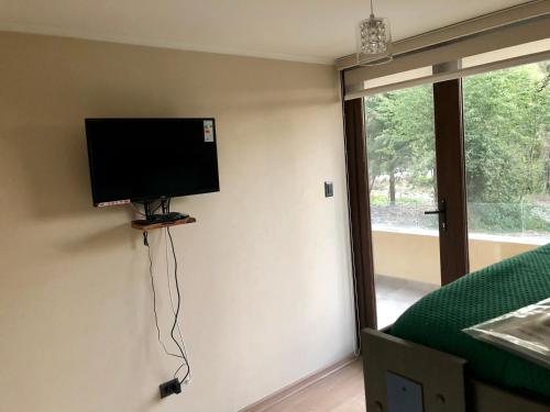 a flat screen tv on the wall of a bedroom at Villarrica Condominio Costanera Playa in Villarrica