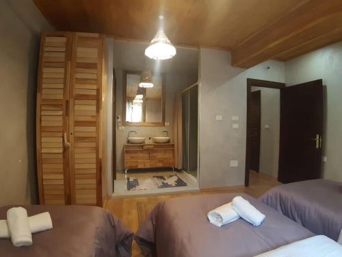 ein Schlafzimmer mit 2 Betten und ein Badezimmer mit einem Waschbecken in der Unterkunft Hotel Restaurant Alpet Theth in Theth