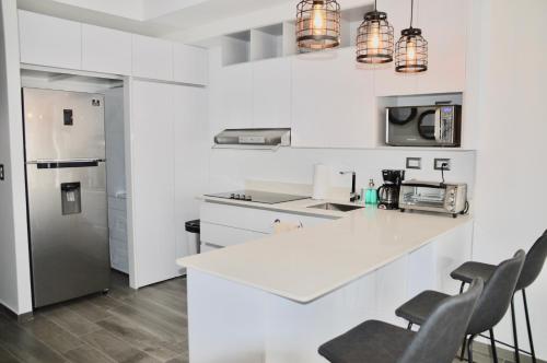 a white kitchen with a white counter and chairs at Cozy Stays Cayala Apartments 3 in Guatemala