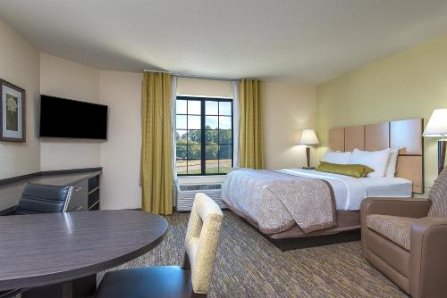 ブルーミントンにあるCandlewood Suites Bloomington, an IHG Hotelのベッドとテーブルが備わるホテルルームです。