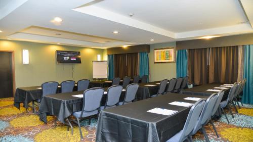 a conference room with tables and chairs and a screen at Holiday Inn Express Hotels & Suites Cuero by IHG in Cuero