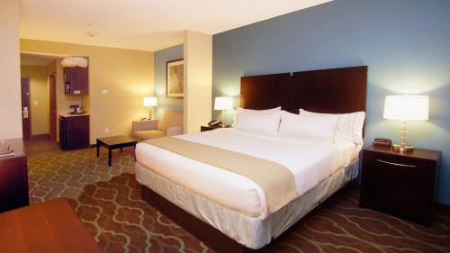 a hotel room with a large bed and a chair at Holiday Inn Express Hotels & Suites Cuero by IHG in Cuero