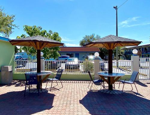 two tables and chairs with umbrellas on a patio at Gulf Way Inn Clearwater in Clearwater