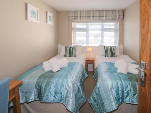 two twin beds in a room with a window at Guillemot in Holywell Bay