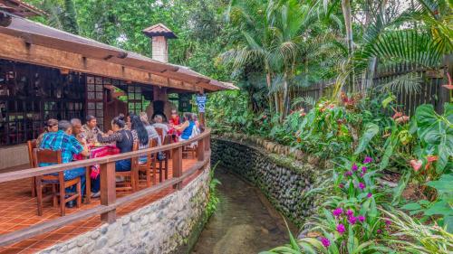 a group of people sitting at a restaurant in a garden at El Jardín Hotel & Restaurante in Puyo