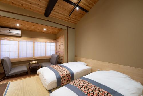 een kamer met 2 bedden, een stoel en een raam bij 至誠宿 SHISEI-JUKU Omiya-Gojo in Kyoto