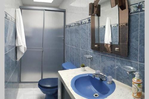 y baño con lavabo azul y aseo. en Confortable casa Armenia, en Armenia