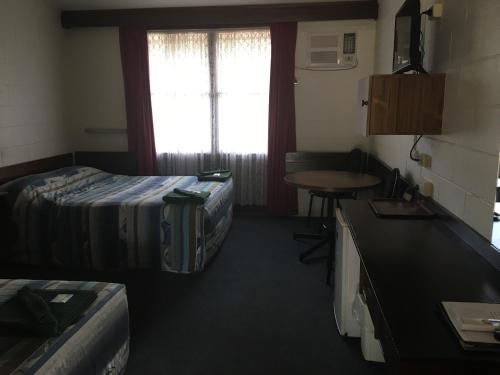 a room with two beds and a table and a window at Peppercorn motor inn in Narromine