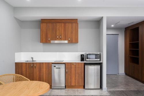 a kitchen with wooden cabinets and stainless steel appliances at Abode Malua Bay in Malua Bay