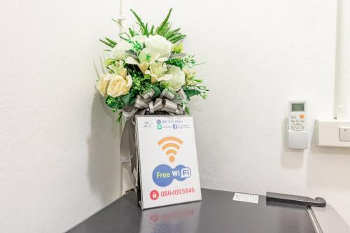 a vase of flowers sitting on a table next to a box at Ze Residence Bang Aor Station in Bangkok