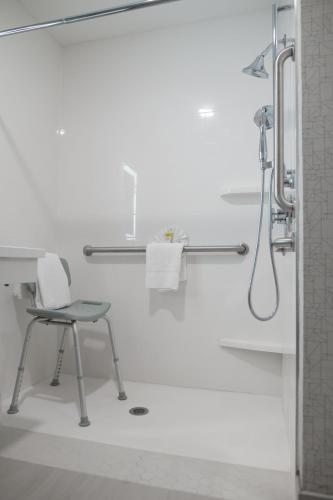 a white bathroom with a chair and a shower at Holiday Inn Express & Suites - Lake Forest by IHG in Lake Forest