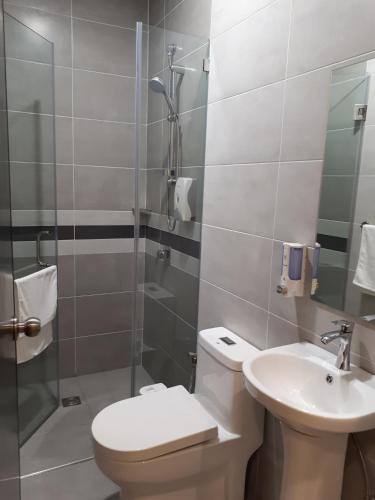 a bathroom with a toilet and a sink and a shower at Hotin Inn in Kuching