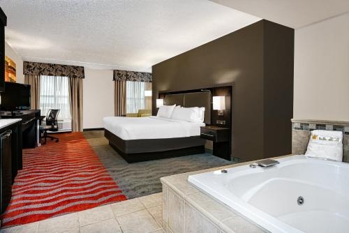 a hotel room with a bed and a tub at Holiday Inn & Suites College Station-Aggieland by IHG in College Station