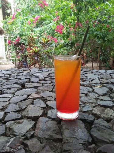 a glass of orange juice sitting on a stone table at Sanctuaria Treehouses Busuanga in Busuanga
