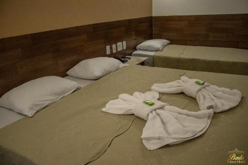 a group of three beds with white towels on them at Bento palace hotel in Assis