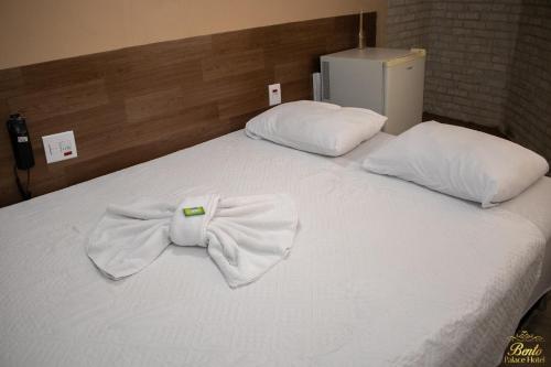 a white bow tie on a bed with two pillows at Bento palace hotel in Assis