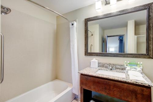 a bathroom with a tub and a sink and a mirror at Holiday Inn Express & Suites Raceland - Highway 90 by IHG in Raceland
