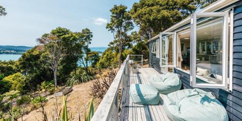 Waiheke Island Motel في Ostend: منزل به سطح خشبي عليه كراسي