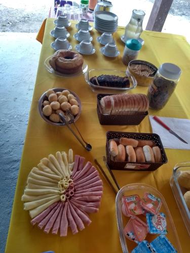 een tafel met een geel tafelkleed met voedsel erop bij Residencial Villa Nova in Boicucanga